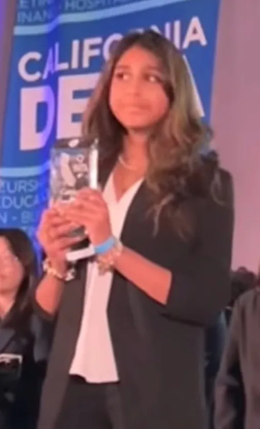 DECA award winner holding her trophy on stage