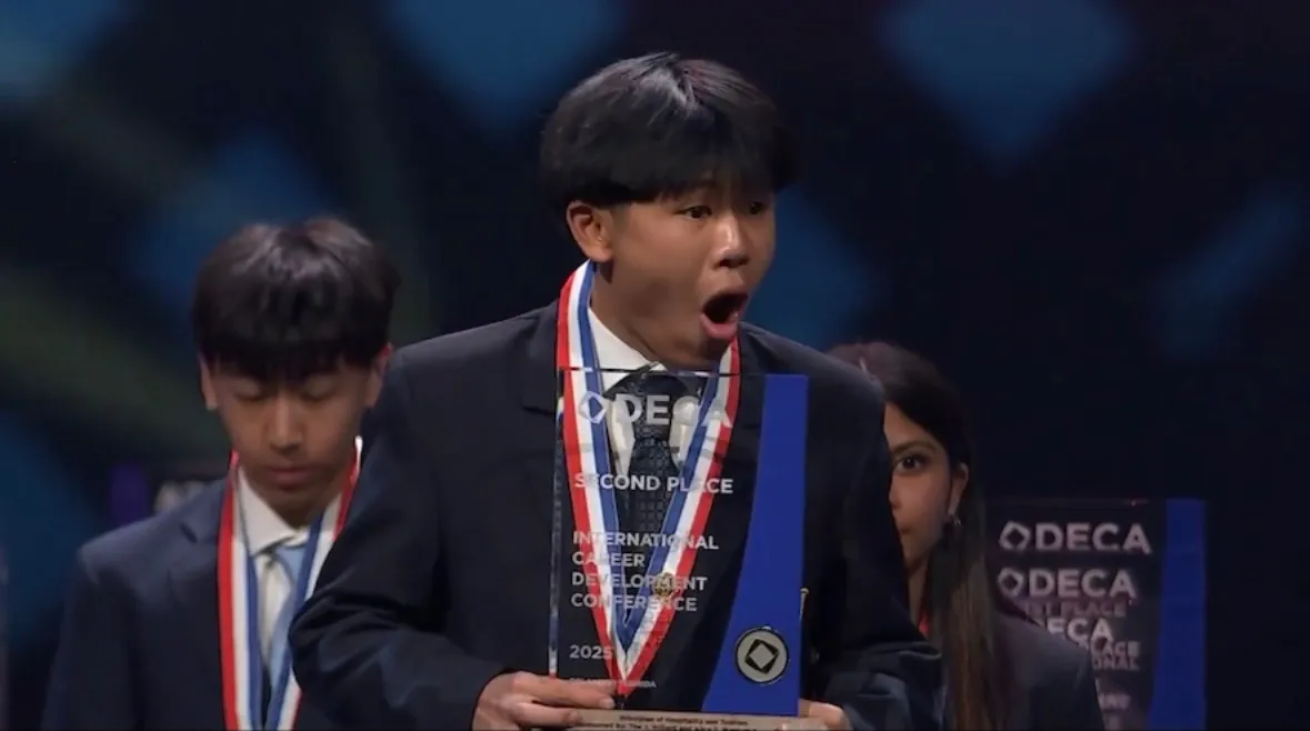 DECA ICDC second-place winner holding his glass trophy on stage