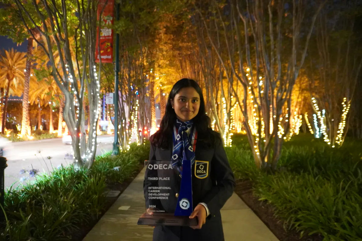 DECA ICDC third-place winner holding her glass trophy