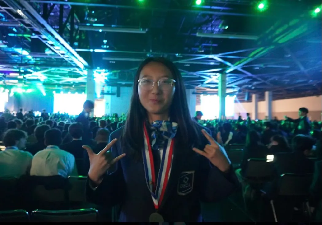 Erika Wu wearing a DECA medal in the ICDC auditorium